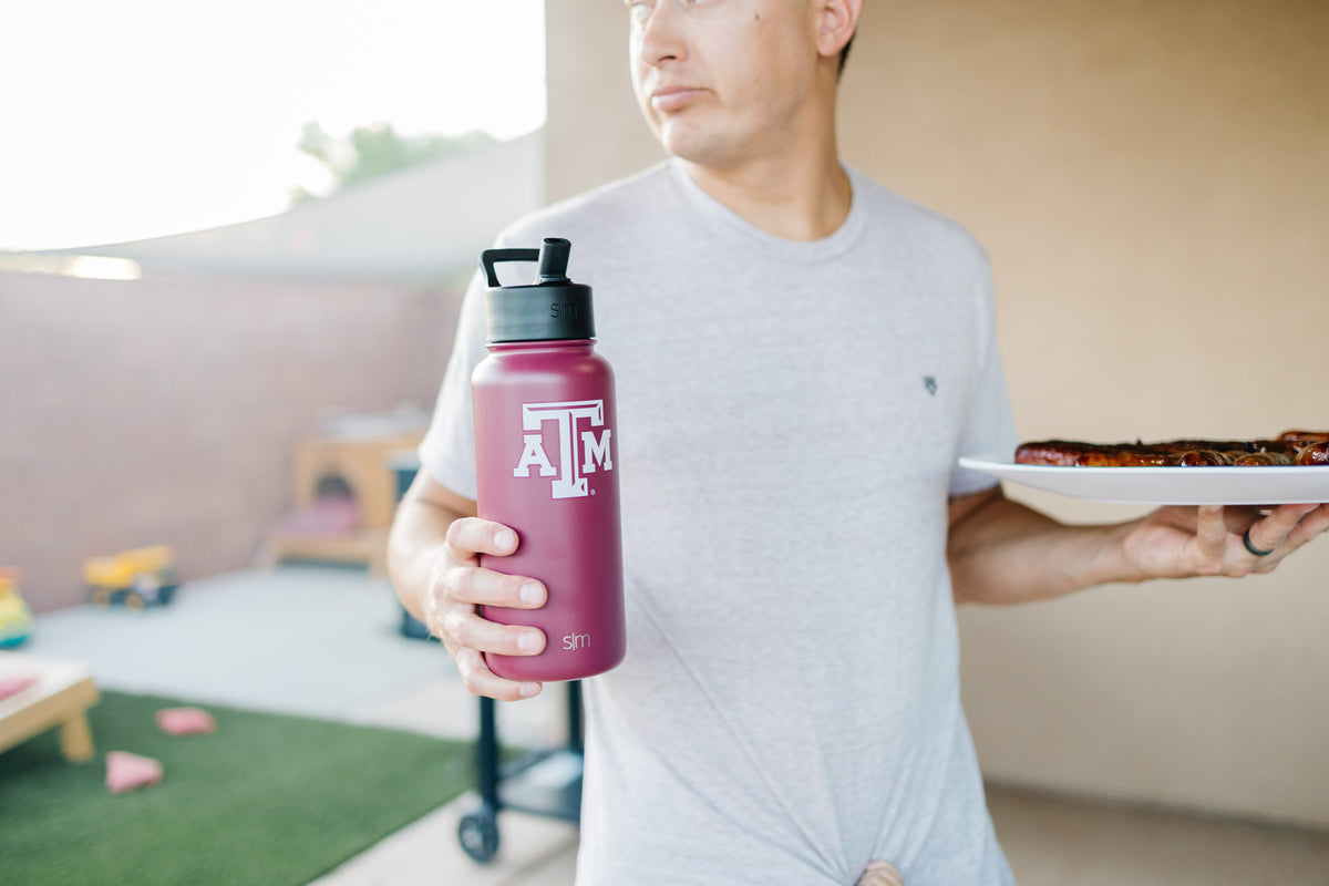 Burgundy water bottle held against light gray t-shirt with warm beige and tan background