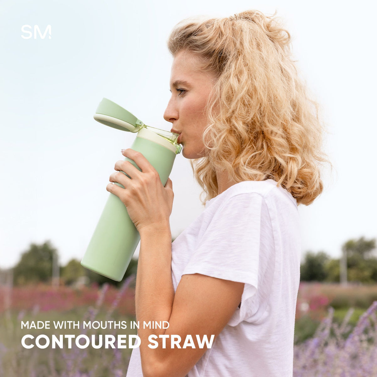 Woman holding a pale sage green contoured drinking vessel with a straw against a soft white and lavender background