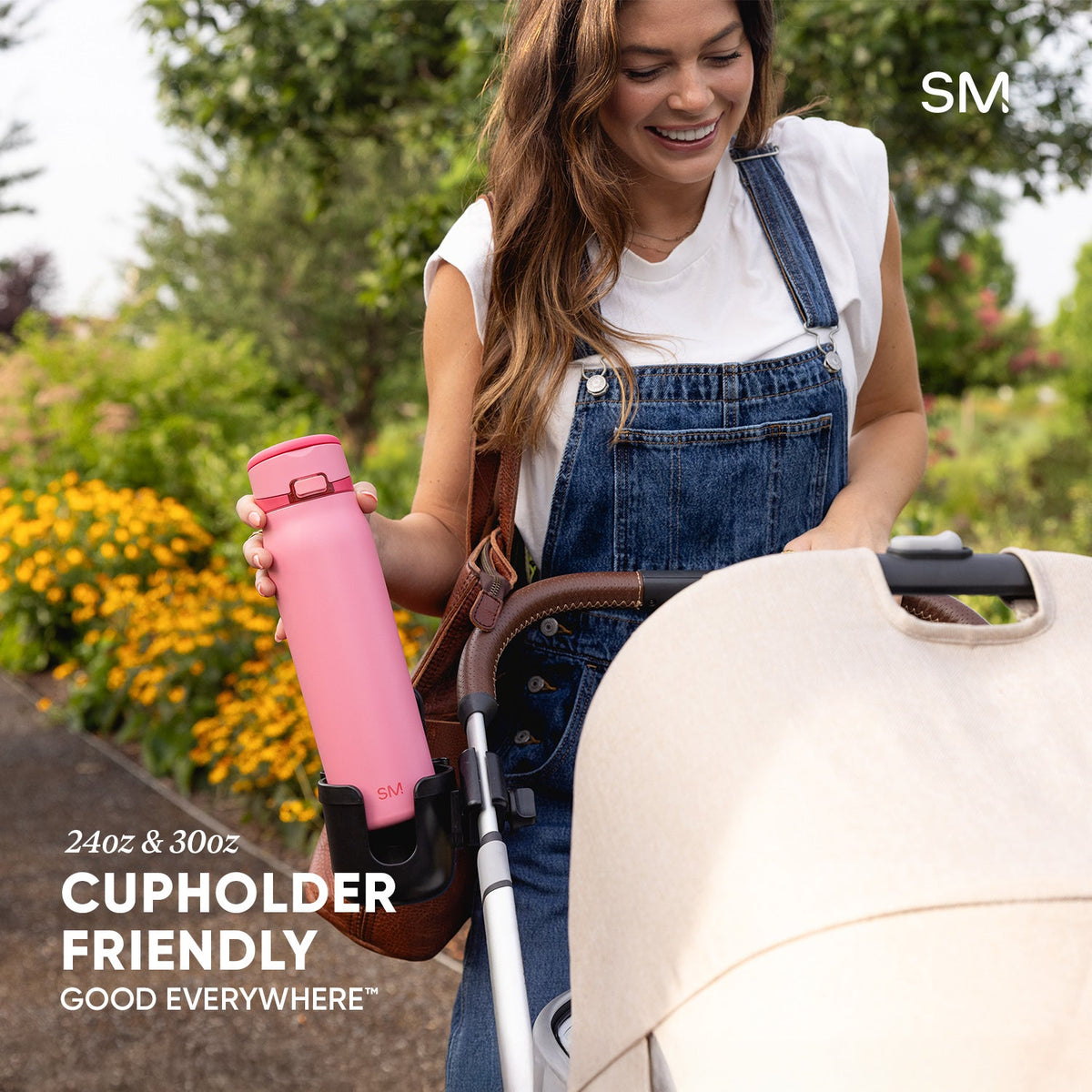 Pink water bottle in cupholder of white outdoor chair with green foliage background, demonstrating Mesa Loop's cup holder-friendly design.